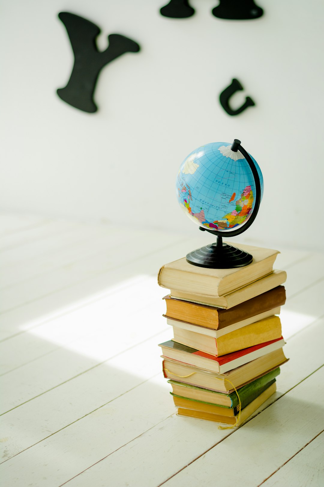 blue-and-yellow-desk-globe-on-yellow-and-white-books-xsofsfb5hco